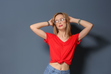 Attractive young woman in stylish outfit on color background