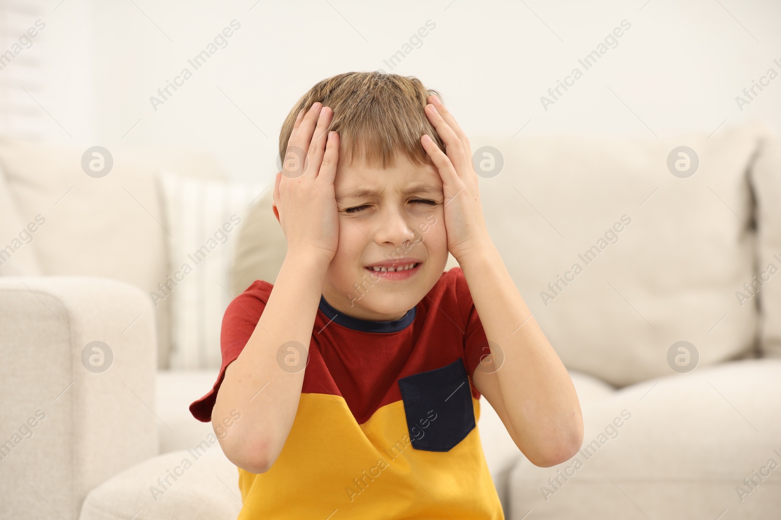 Photo of Little boy suffering from headache at home