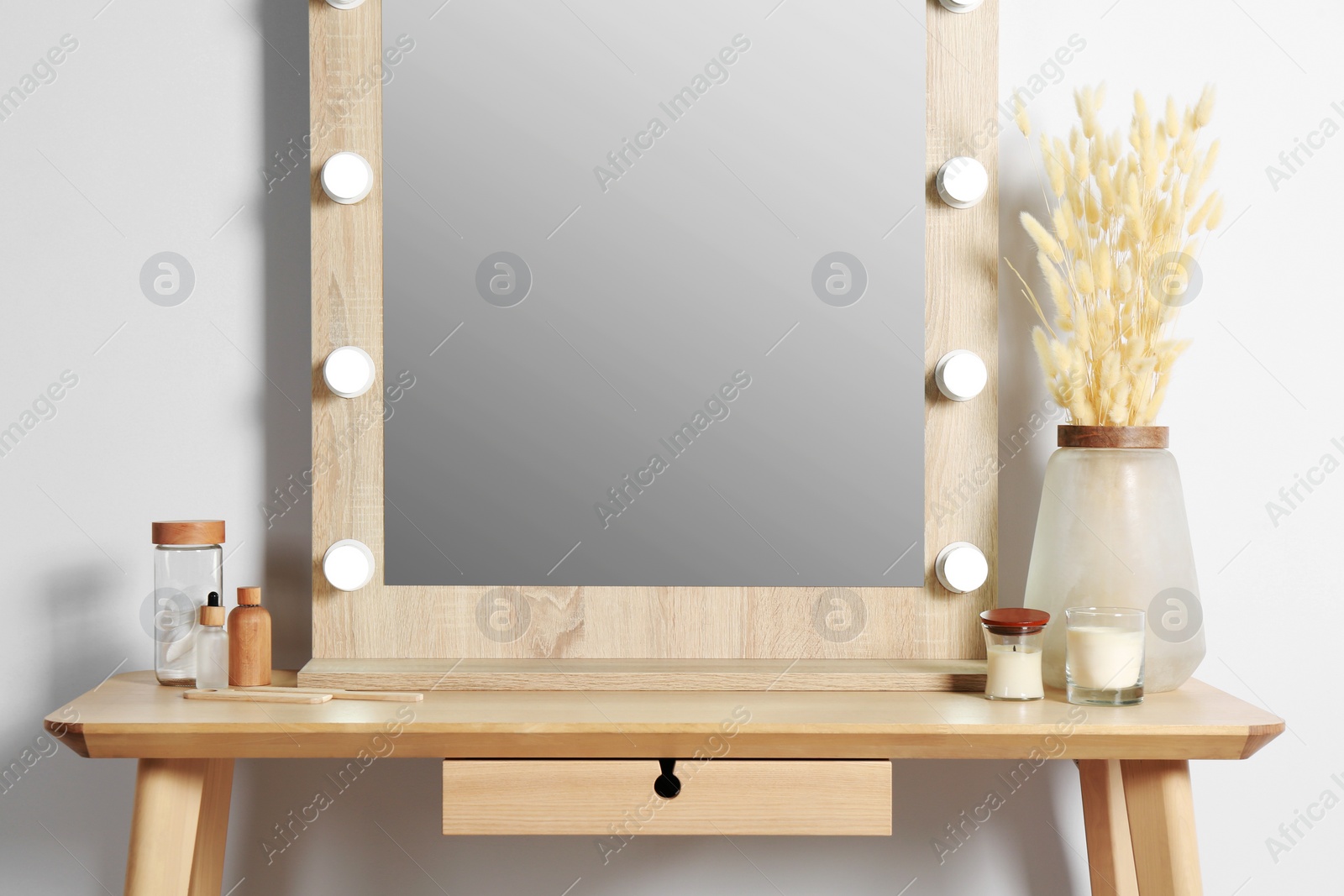 Photo of Dressing table with stylish mirror, dried reeds and other decorative elements. Interior design