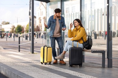 Photo of Being late. Worried couple with suitcases at bus station outdoors
