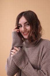 Portrait of beautiful young woman in warm sweater on brown background