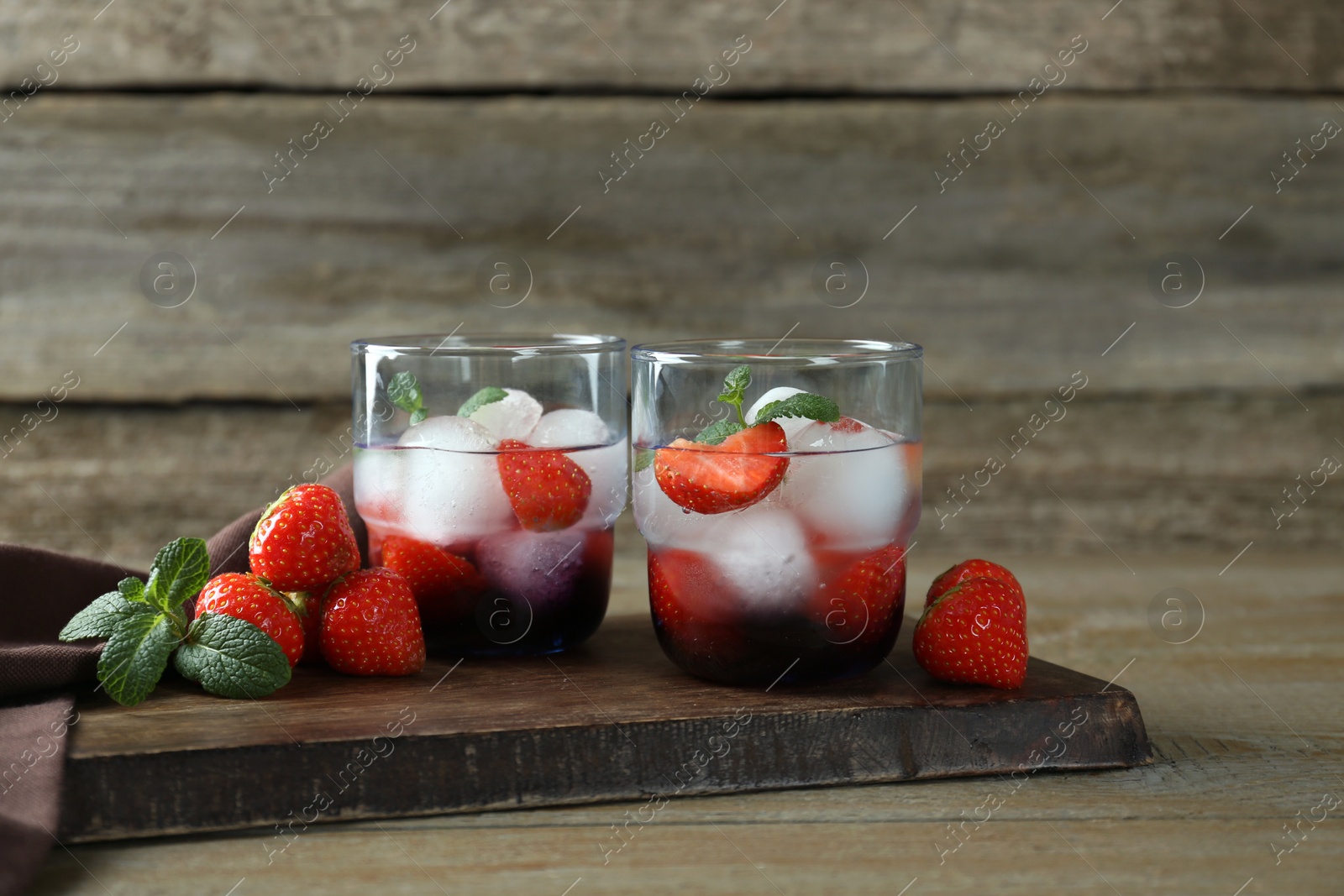 Photo of Delicious cocktails with strawberries, mint and ice balls on wooden table