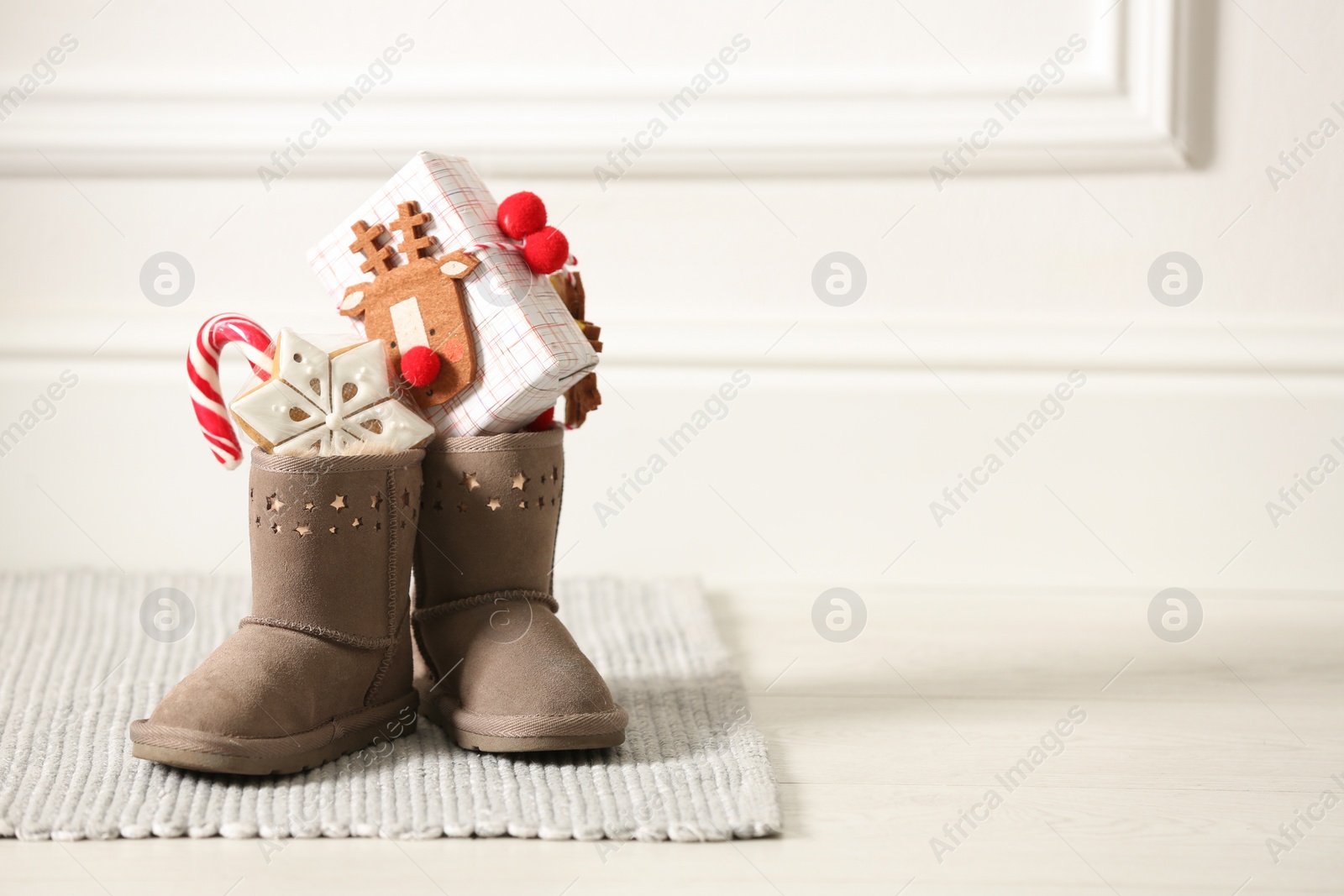 Photo of Sweets and gift box in child's boots indoors, space for text. St. Nicholas Day tradition