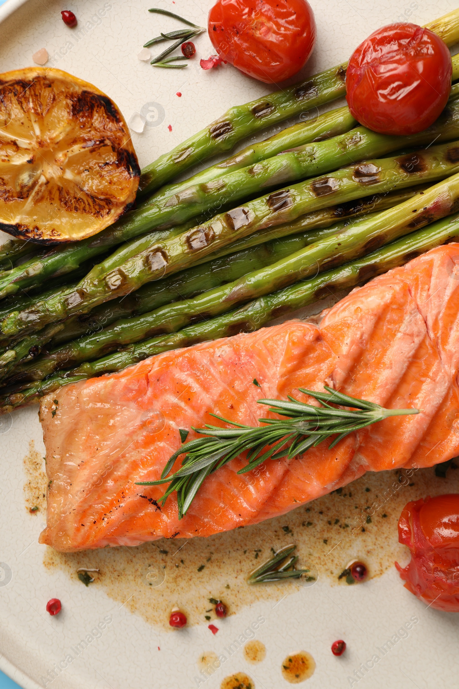 Photo of Tasty grilled salmon with tomatoes, asparagus and spices on plate, top view