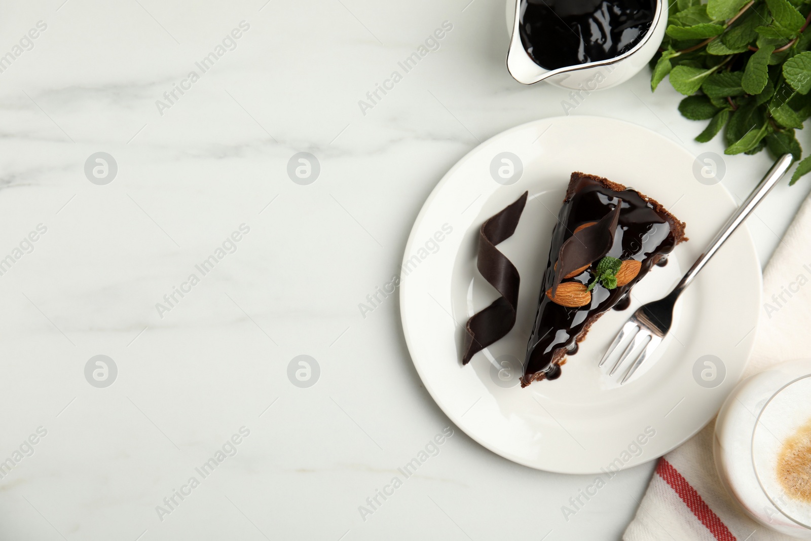 Photo of Piece of tasty homemade chocolate cake served with mint, almonds and coffee on white marble table, flat lay. Space for text