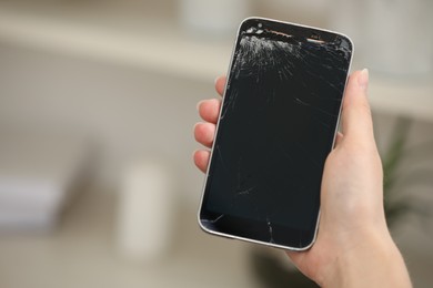 Photo of Woman holding damaged smartphone on blurred background, closeup with space for text. Device repairing