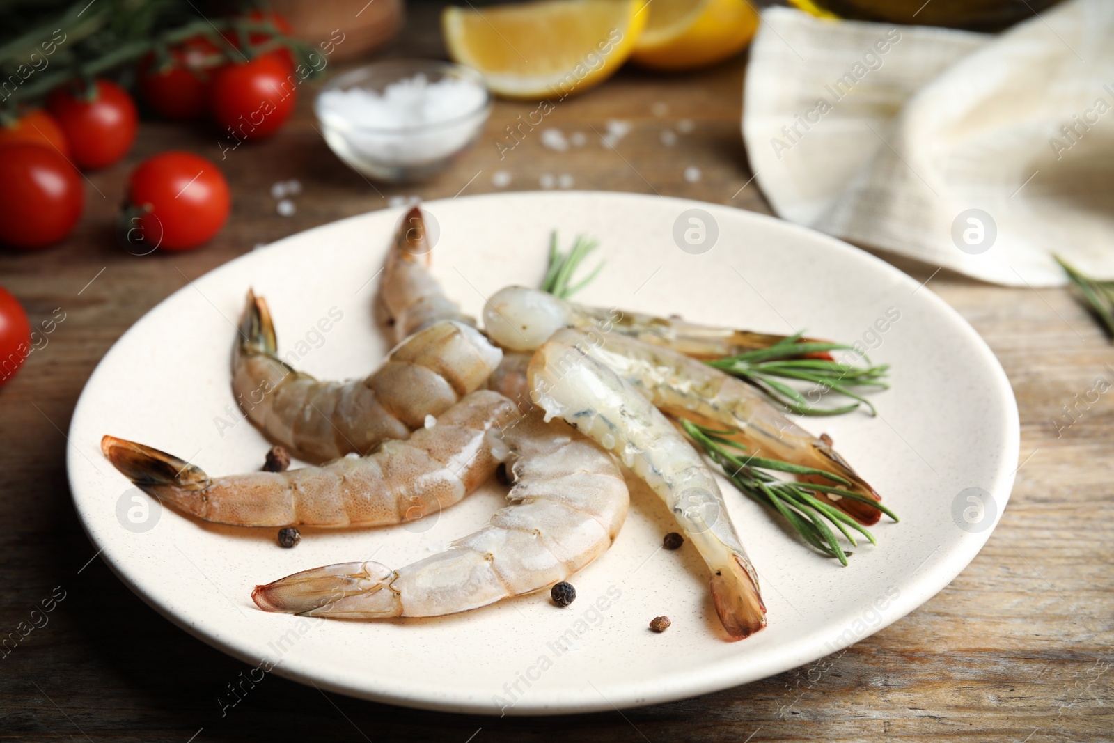 Photo of Fresh raw shrimps with rosemary and pepper on wooden table