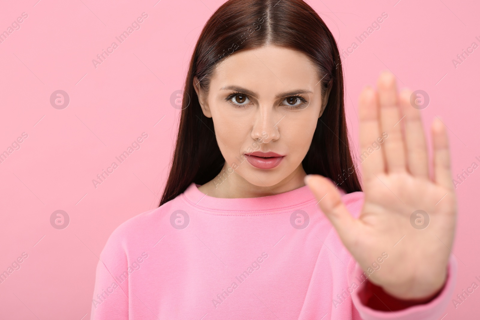 Photo of Woman showing stop gesture on pink background, selective focus