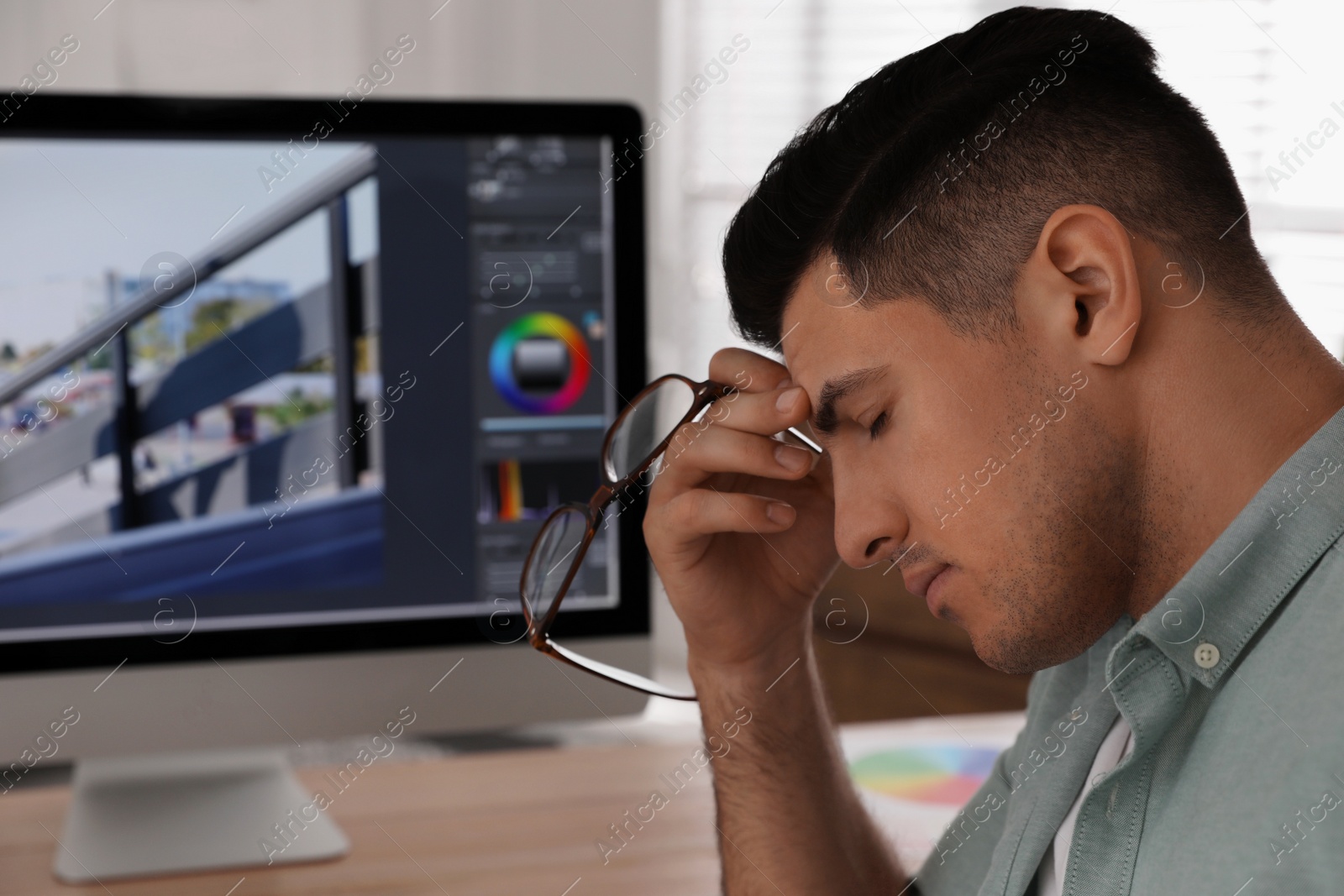 Photo of Tired retoucher at workplace with modern computer