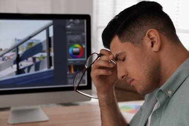 Photo of Tired retoucher at workplace with modern computer