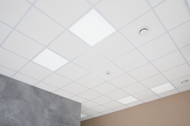 Photo of White ceiling with modern lighting in room, low angle view
