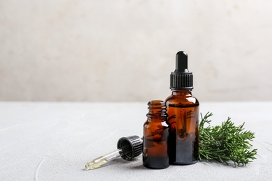 Photo of Composition with bottles of conifer essential oil on light table. Space for text