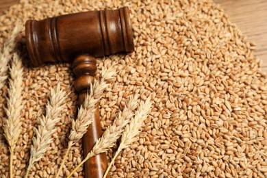 Judge's gavel, wheat ears and grains on wooden table, closeup. Agricultural deal