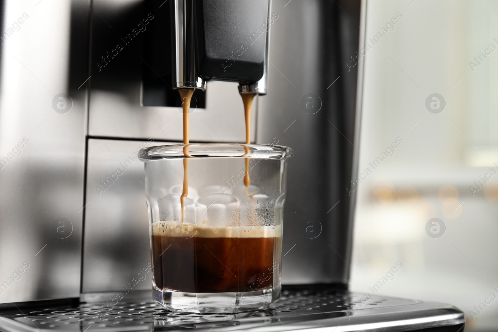 Photo of Espresso machine pouring coffee into glass against blurred background, closeup. Space for text