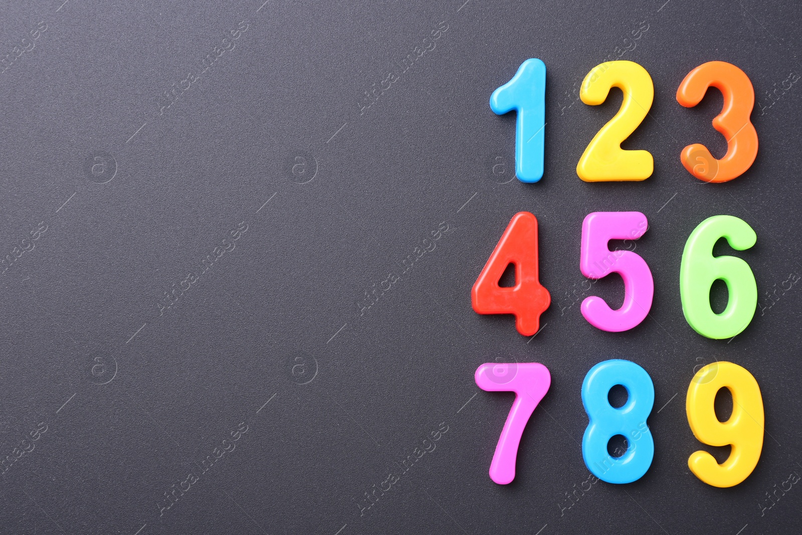 Photo of Colorful numbers on dark gray background, flat lay. Space for text