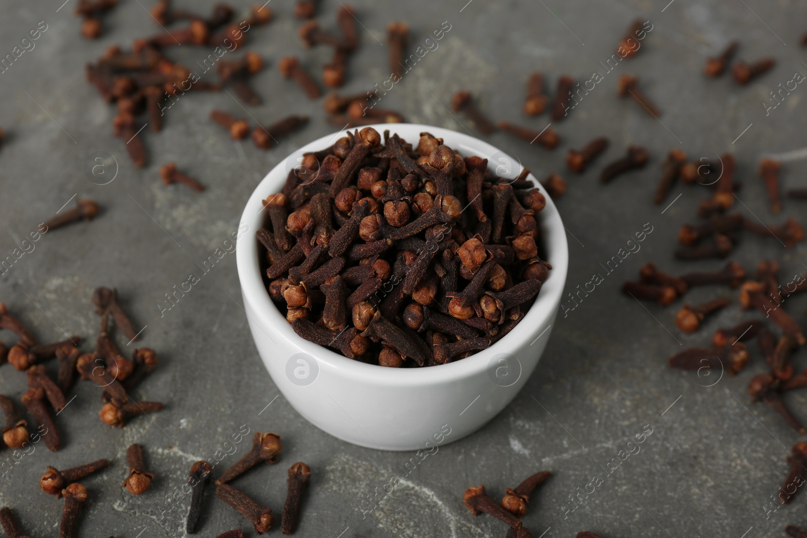 Photo of Ceramic bowl and aromatic dry cloves on grey table