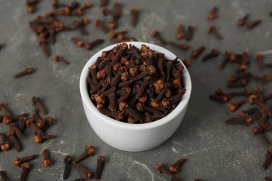 Photo of Ceramic bowl and aromatic dry cloves on grey table