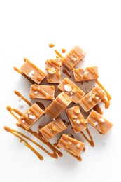 Tasty candies, caramel sauce and salt on white table, top view