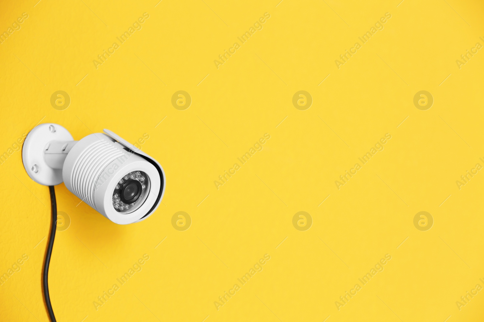 Photo of Modern security CCTV camera on color wall