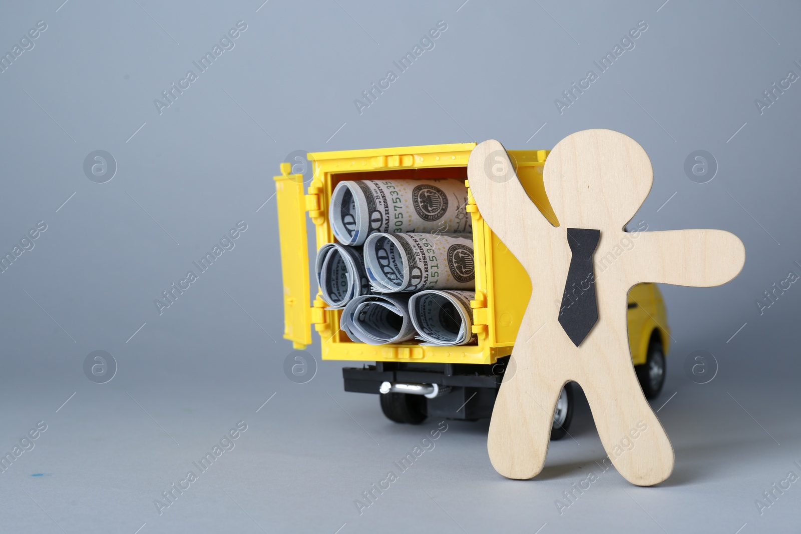 Photo of Economic profit. Wooden figure and toy truck with banknotes on light grey background, space for text