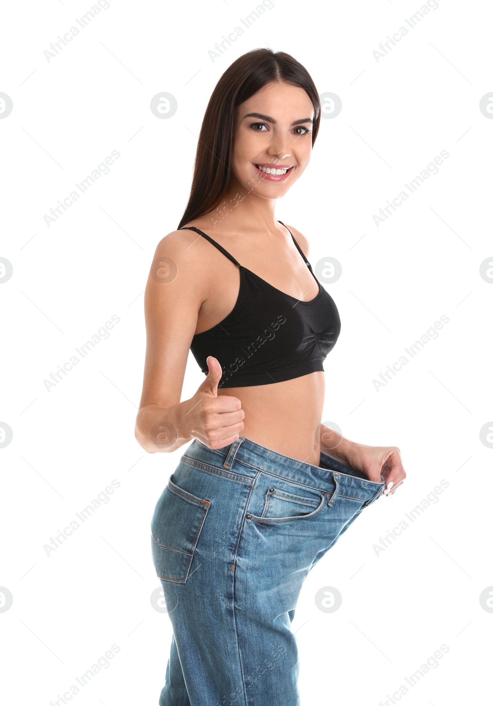 Photo of Attractive young woman with slim body wearing her old big jeans on white background