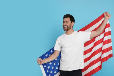 4th of July - Independence Day of USA. Happy man with American flag on light blue background, space for text