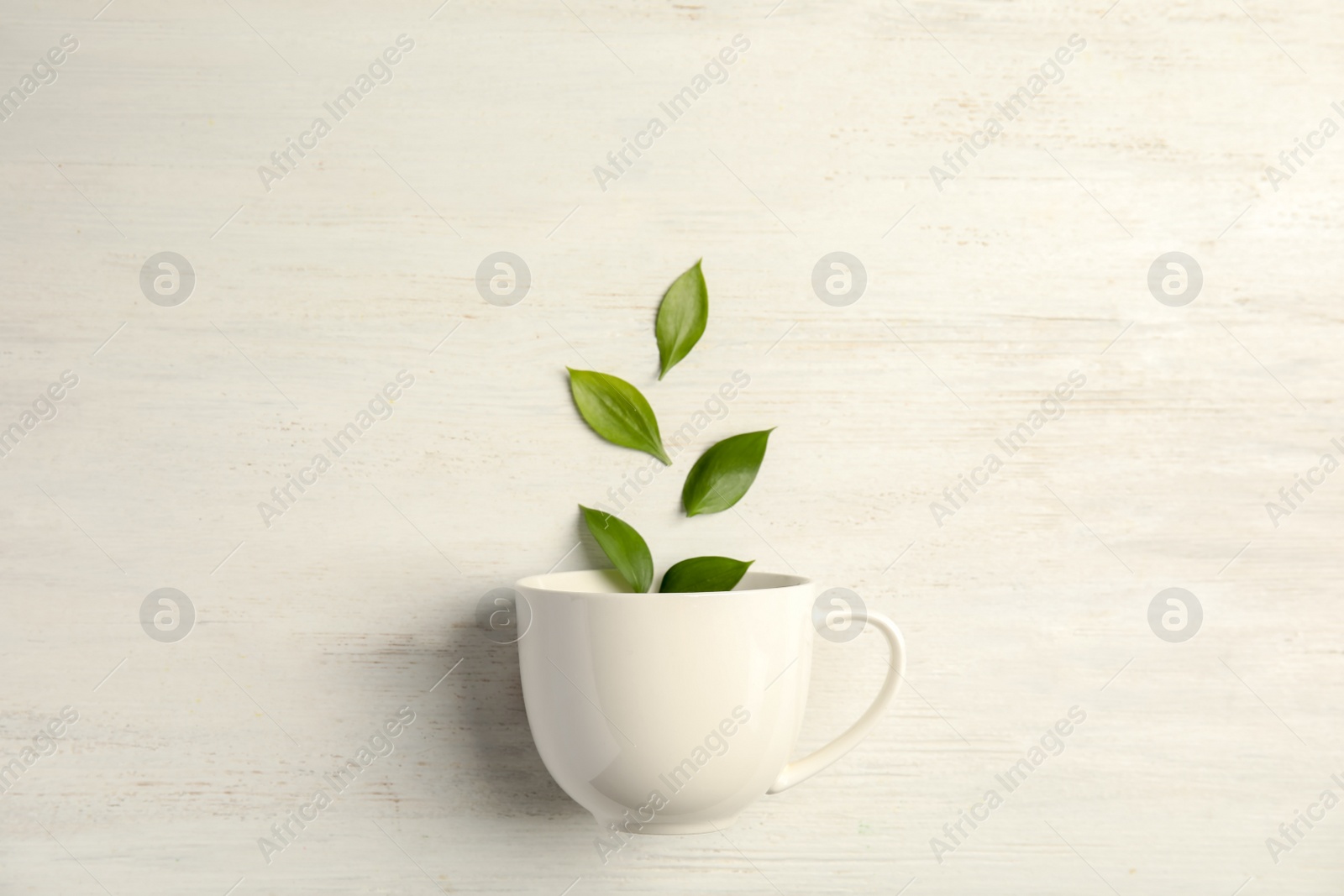 Photo of Flat lay composition with teacup and green leaves on wooden background