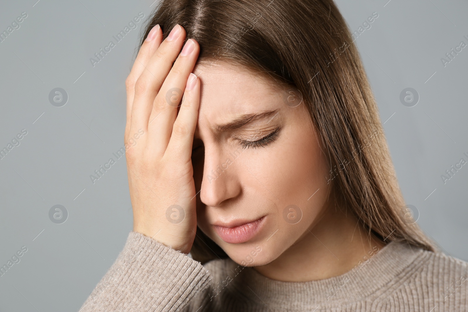 Photo of Young woman suffering from migraine on grey background