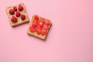 Photo of Tasty peanut butter sandwiches with fresh berries on pink background, flat lay. Space for text