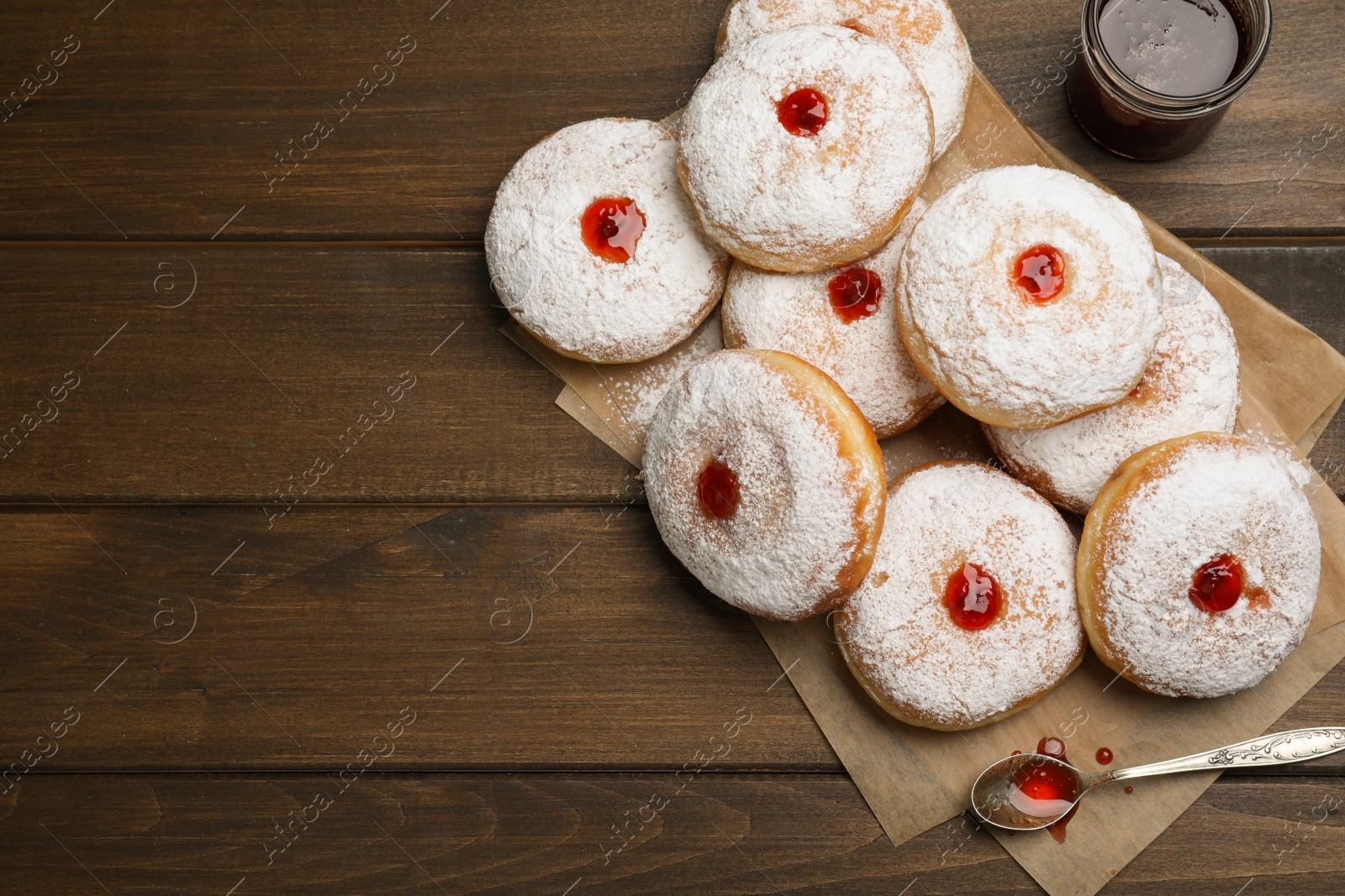 Photo of Many delicious donuts with jelly and powdered sugar on wooden table, flat lay. Space for text