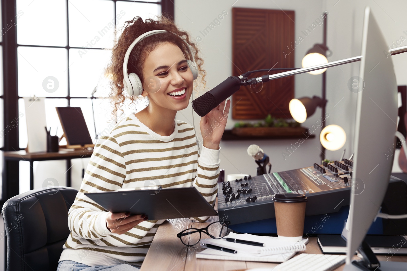 Photo of African American woman working as radio host in modern studio