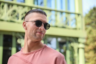 Photo of Portrait of handsome man in sunglasses outdoors, space for text