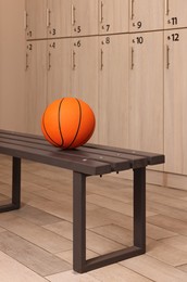 Orange basketball ball on wooden bench in locker room