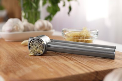 Garlic press with mince on wooden table indoors, closeup