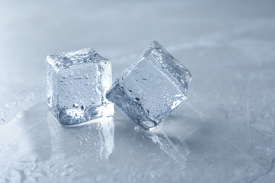 Crystal clear ice cubes with water drops on grey table