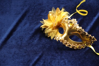 Photo of Theater arts. Golden venetian carnival mask on blue fabric, space for text