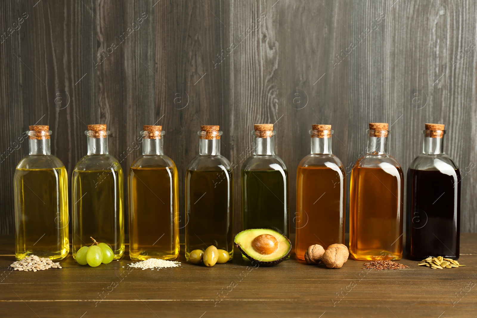 Photo of Vegetable fats. Different oils in glass bottles and ingredients on wooden table