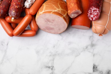Photo of Different types of sausages on white marble table, flat lay. Space for text