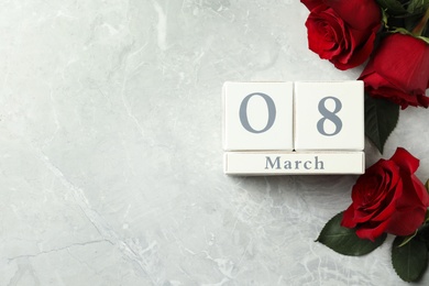 Block calendar with date 8th of March and roses on light grey marble background, flat lay. Space for text