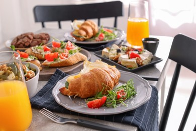 Photo of Tasty croissant sandwich and many different dishes served on buffet table for brunch