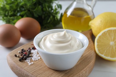 Tasty mayonnaise sauce in bowl, spices and ingredients on table, closeup