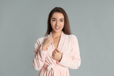 Photo of Beautiful young woman in bathrobe on grey background