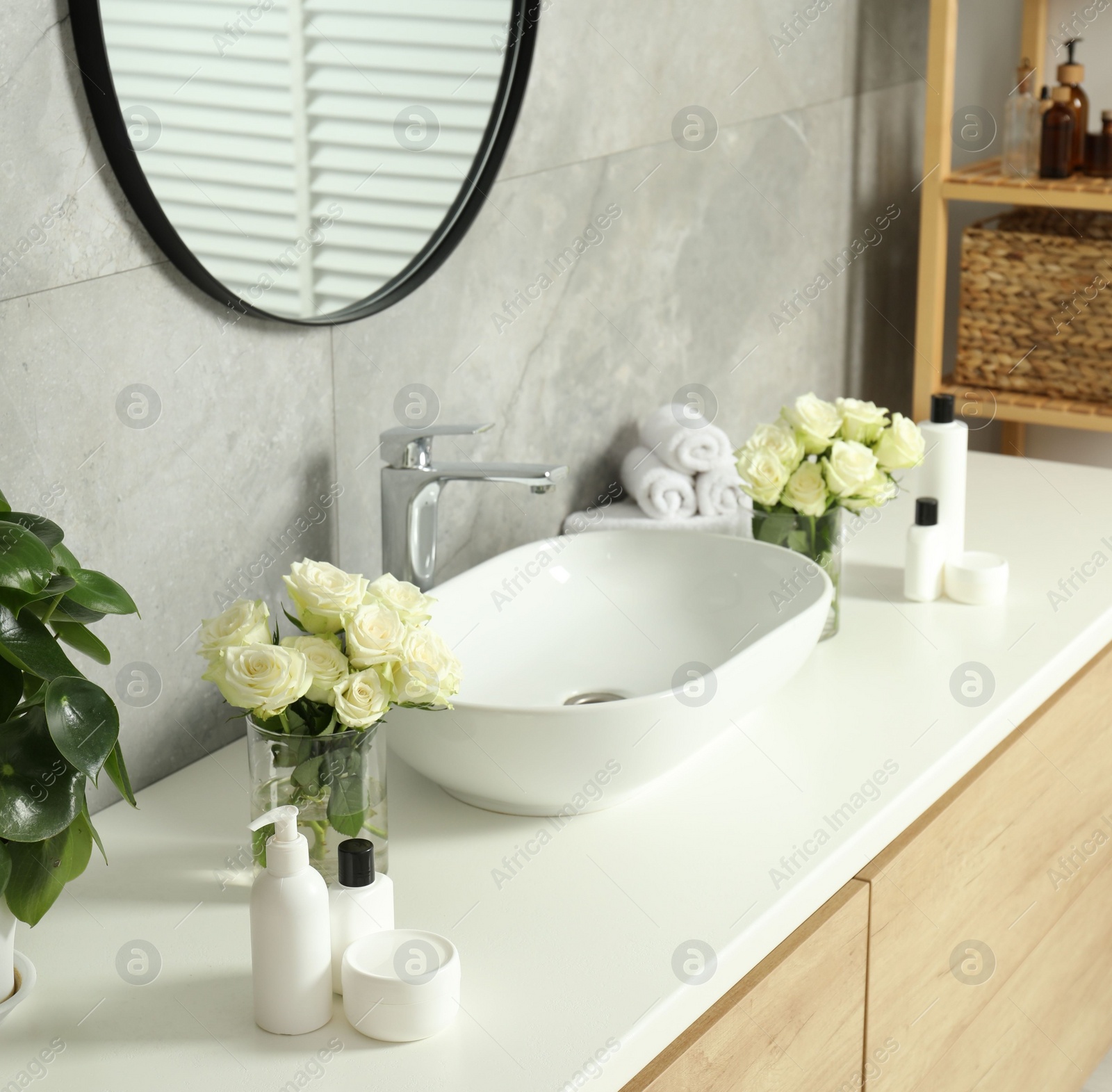 Photo of Beautiful roses and bath accessories near sink in bathroom