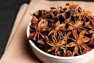 Photo of Bowl with aromatic anise stars on table, closeup