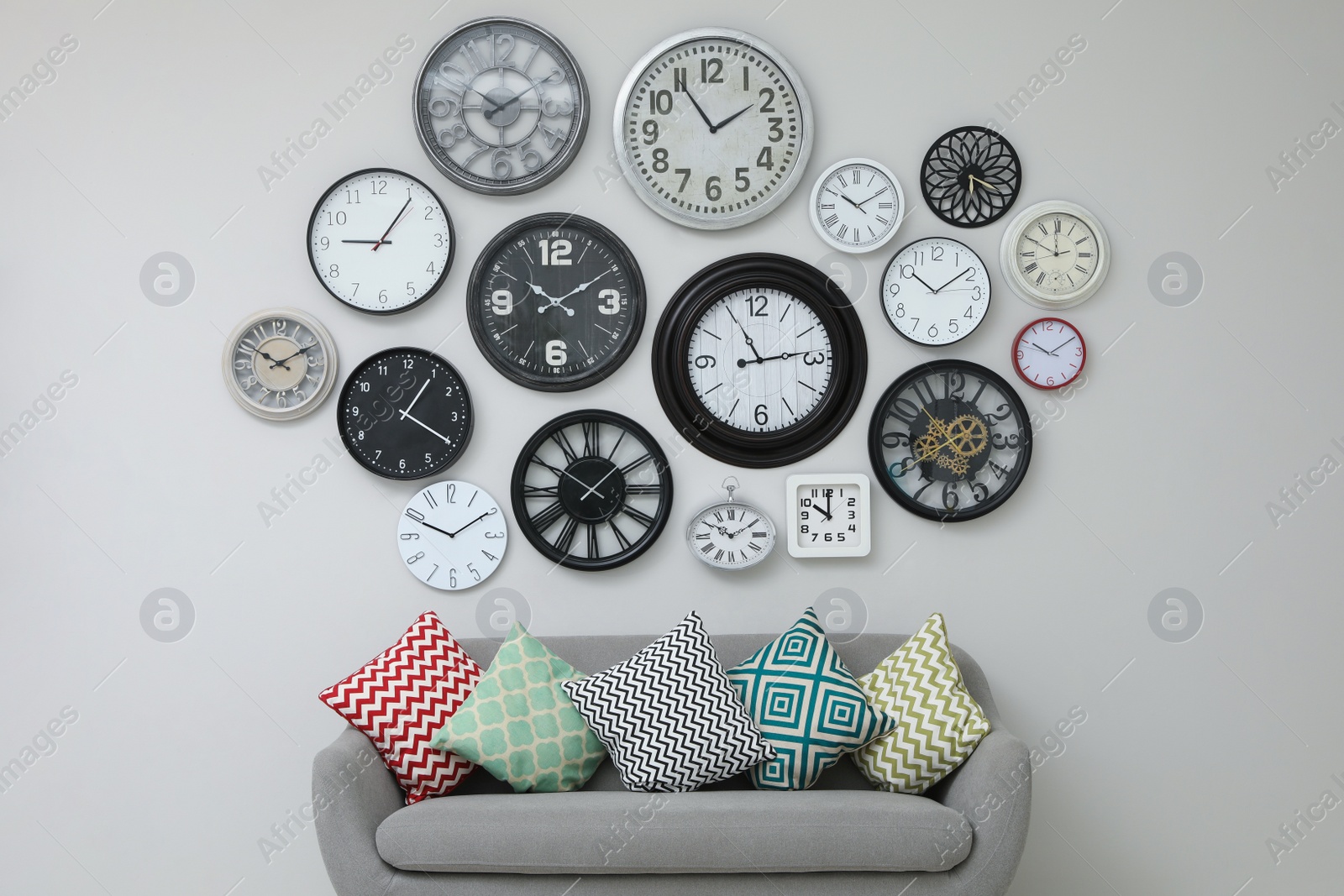 Photo of Sofa and many different clocks hanging on white wall in room