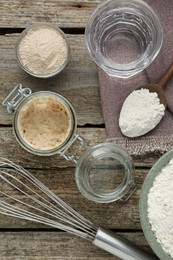 Leaven, flour, whisk and water on wooden table, flat lay