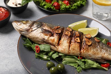 Photo of Delicious sea bass fish and ingredients on light grey table, closeup