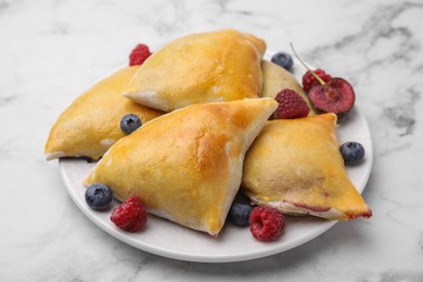 Photo of Delicious samosas with cherry and berries on white marble table, closeup