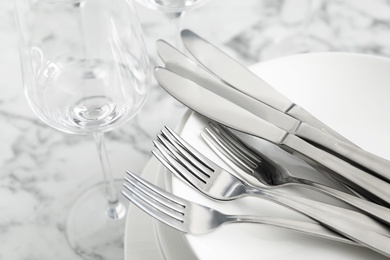 Photo of Plates with knives forks on white marble table, closeup