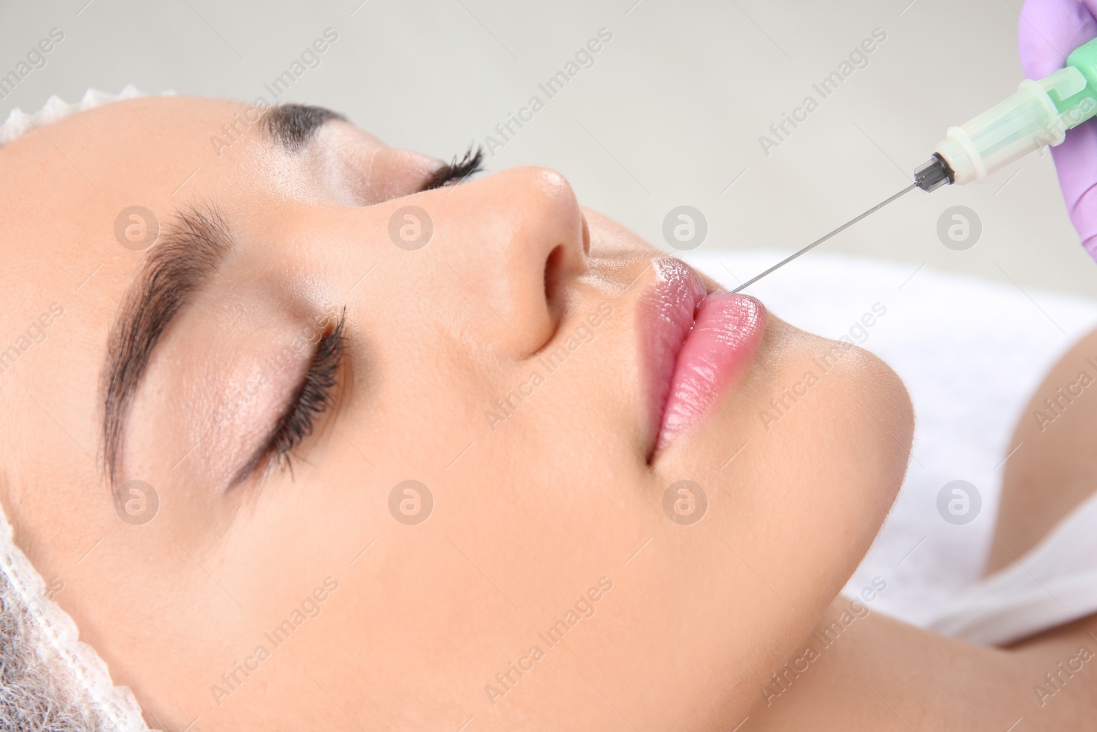 Photo of Young woman getting lip injection in beautician salon, closeup